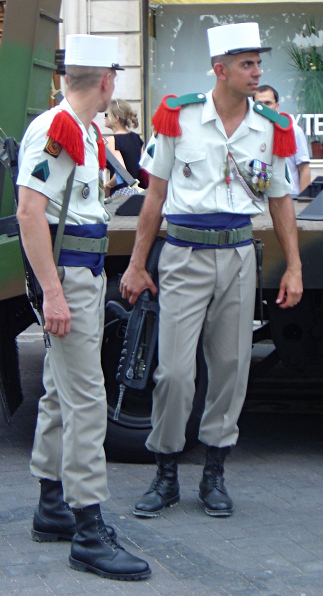 Żołnierze Legii Cudzoziemskiej podczas przerwy w dniu defilady z okazji Święta Narodowego Francji. Czerwone naramienniki oraz białe kepi stanowią charakterystyczne elementy umundurowania tej słynnej formacji. Obowiązkowo - z karabinem FAMAS.