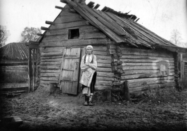Kobieta z powiatu sarneńskiego obok swojego walącego się domu. Choć dziś nie chcemy o tym pamiętać, ogromne rzesze ludności żyły w skrajnej biedzie. (fot. domena publiczna)