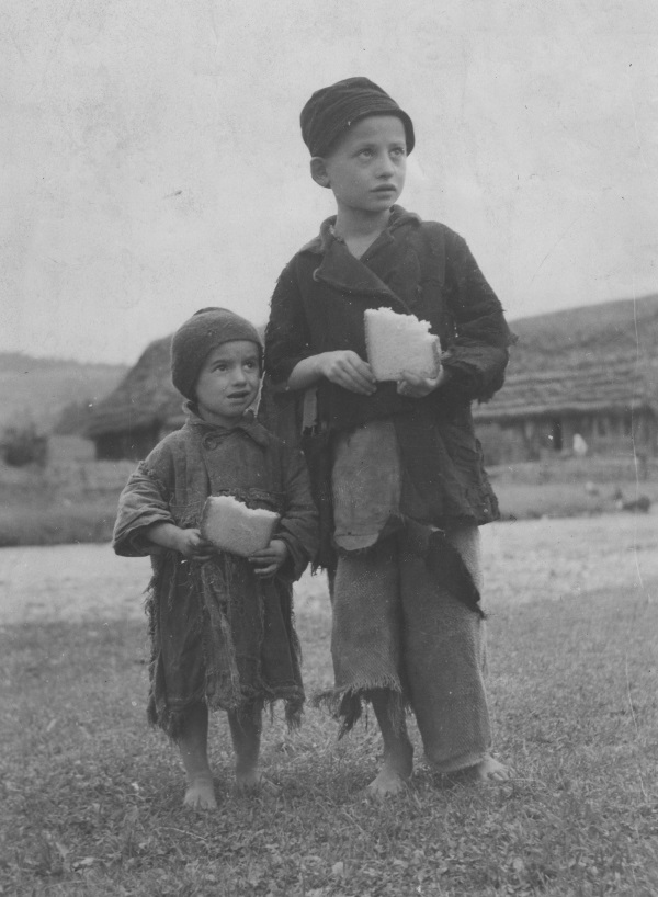 Ubodzy obdarci chłopcy posilający się kromką chleba. (fot. domena publiczna)