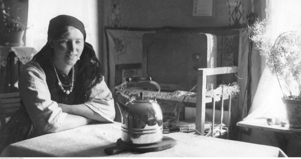 Wiejska kobieta wpatruje się niepewnie w czajnik elektryczny. Wreszcie aby zagotować wodę na herbatę nie trzeba pędzić po drewno. Ilustracja i podpis pochodzą z książki "Dwudziestolecie od kuchni" Zaprutko-Janickiej.